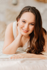 portrait of a pregnant woman in white peignoir in bed. sexy clothes.