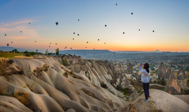 Smartphone in hands of woman taking pictures of a beautiful landscape and balloons in Cappadocia. Sunrise time, dreamy travel concept
