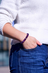 Vertical image of a natural amethyst bracelet on a female hand, close-up