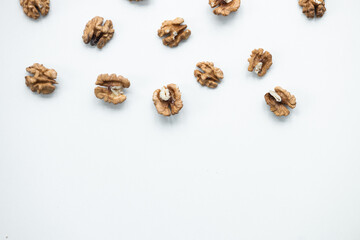 Halves of walnuts on white background, pattern, top view.