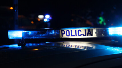 Nocna interwencja alarmowa policji - Sygnalizator błyskowy niebieski na dachu radiowozu policji polskiej w nocy. - obrazy, fototapety, plakaty