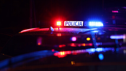Nocna interwencja alarmowa policji - Sygnalizator błyskowy niebieski na dachu radiowozu policji polskiej w nocy. - obrazy, fototapety, plakaty