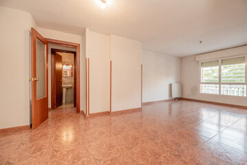 Empty room with reddish ceramic stoneware floors, reddish wooden doors with glass and cream white painted walls