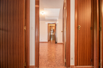 Fototapeta na wymiar distributor of a house with reddish ceramic stoneware floors, reddish wooden doors with glass and cream white painted walls