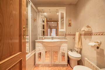 Small bathroom of home with white shower stall, wall mirror and porcelain sink on white wooden...