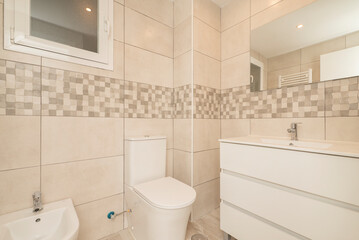Small modern bathroom with frameless mirror on the wall, white porcelain fixtures and white chest of drawers