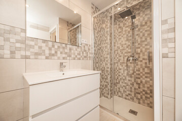 Small modern bathroom with frameless mirror on the wall, glass sliding door shower stall and white...