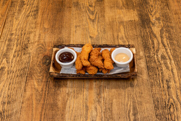 Delicious plate of battered and fried chicken fingers with dipping sauces