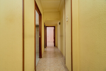 Yellow painted corridor with entrance to several rooms and ceramic tile floors