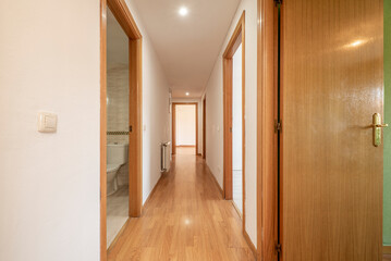 Plain white painted hallway with entry to multiple rooms and oak parquet flooring