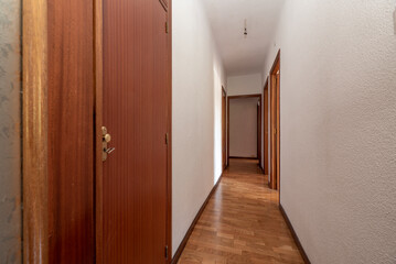 Plain white painted corridor with entrance to various rooms, fitted wardrobes and oak parquet floor