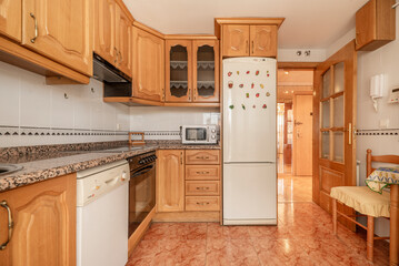Kitchen with country-style wooden furniture, reddish stoneware floors, integrated appliances and pink granite countertops