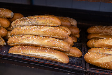 A variety of bread products with sesame: buns, pretzels, poppy seed buns for sale in a bakery
