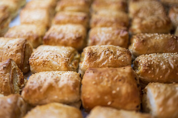 A variety of bread products with sesame: buns, pretzels, poppy seed buns for sale in a bakery
