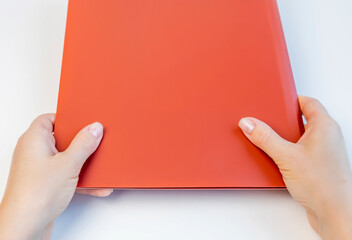 Female hands hold a folder for documents above the table.