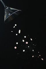 Martini style glass spilling over and pouring out a selection of drugs and or medication. Black background drug or medical concept with copy space