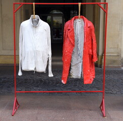Weißes Hemd und rote Jacke auf einem Kleiderständer auf der Straße stehend