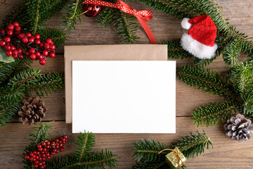 Fototapeta na wymiar Christmas 7x5 card mockup template with envelope with fir twigs and Christmas decor on wooden background. Design element for Christmas and New Year congratulation, greeting or invitation card