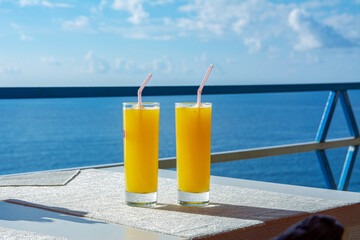 Two glasses of orange sit on a table in a seaside cafe at a seaside resort
