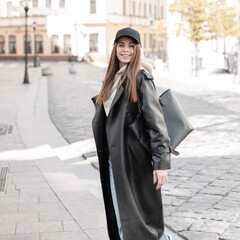 Beautiful fashionable young woman model with a cap in stylish black outwear look with a denim...
