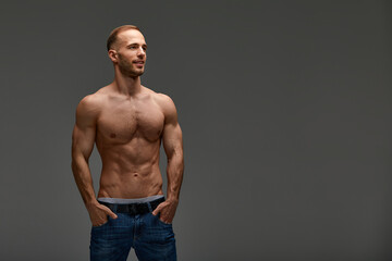Young male athlete posing. Handsome athletic male power guy. Fitness muscular person. Young athlete showing muscles in the studio, posing shirtless on gray background.