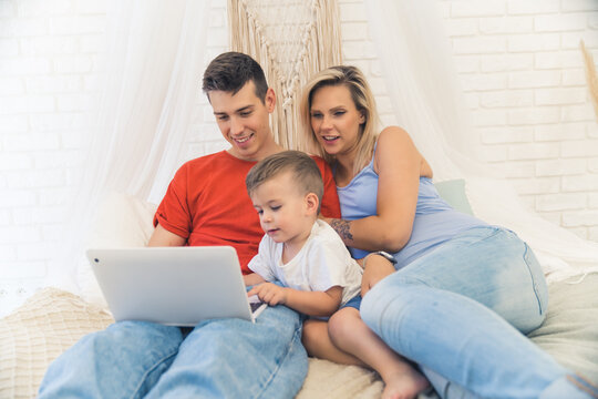 happy Caucasian family with kid son enjoying by using laptop at the home medium full shot. High quality photo