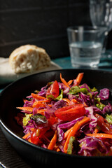 Red cabbage salad with carrots and cherry tomatoes. Close-up with selective focus.