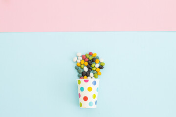 many different candies , sweets in paper cup on blue background