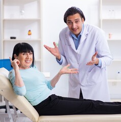 Old woman visiting young doctor laryngologist