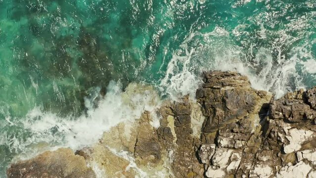 Aerial view blue ocean waves crashing against a rocky shore. Background video of beautiful sea landscape.