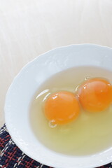 Double raw egg in white bowl with copy space