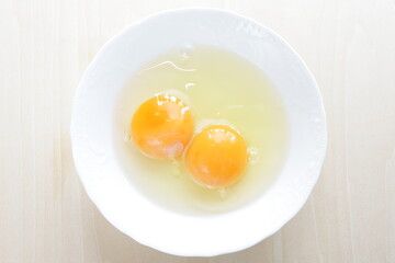 Double raw egg in white bowl with copy space
