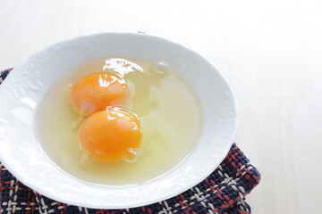 Double raw egg in white bowl with copy space