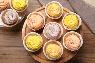 Stand with tasty cupcakes on wooden table, flat lay