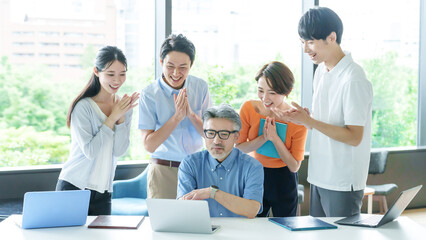 Obraz premium パソコンを見ながら拍手をするビジネスパーソン