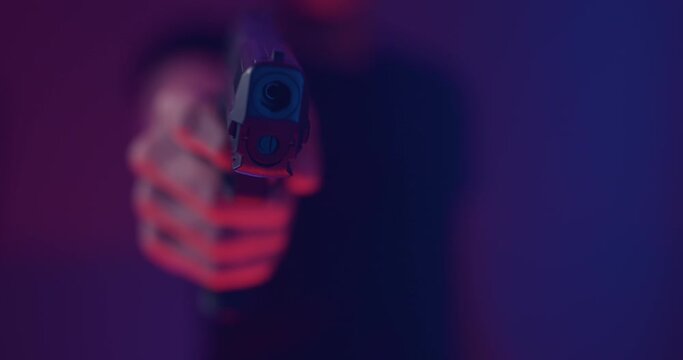 Close up of hand raising and aiming pistol towards camera and pulling trigger