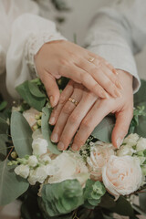 two hands with wedding ring holding flowers or bouquet