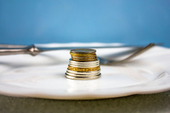 Fork and knife with coins in a plate.The concept of rising food prices.The concept of a famine scene. Rising food prices.