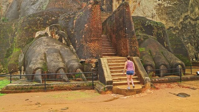 Caucasian female tourist hiking up the stairs of Lion's Paw which leads to the Lion's Rock Fortress in Sigiriya, Sri Lanka