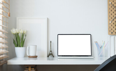 Contemporary workplace with laptop computer, picture frame, stationery and flower pot. Blank screen for your advertise text.