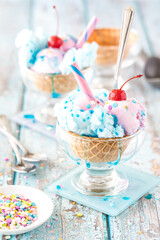Cotton candy sundae in waffle bowls, garnished with sprinkles and syrup.