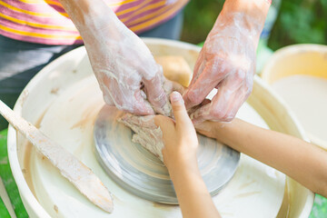 Potter making a clay object on pottery wheel in outdoors. Craftsman moulding clay with hands on pottery wheel. Potter shows a clay modeling master class