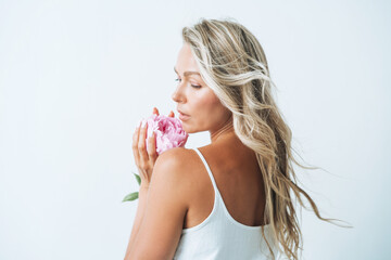 Beauty portrait of blonde hair young woman with pink peony in hand isolated on white background