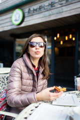 A woman in a cafe eats waffles for dessert and sends out an air kiss. Vertical photo.