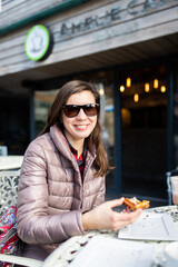 A woman in a cafe eating waffles for dessert. Vertical photo.