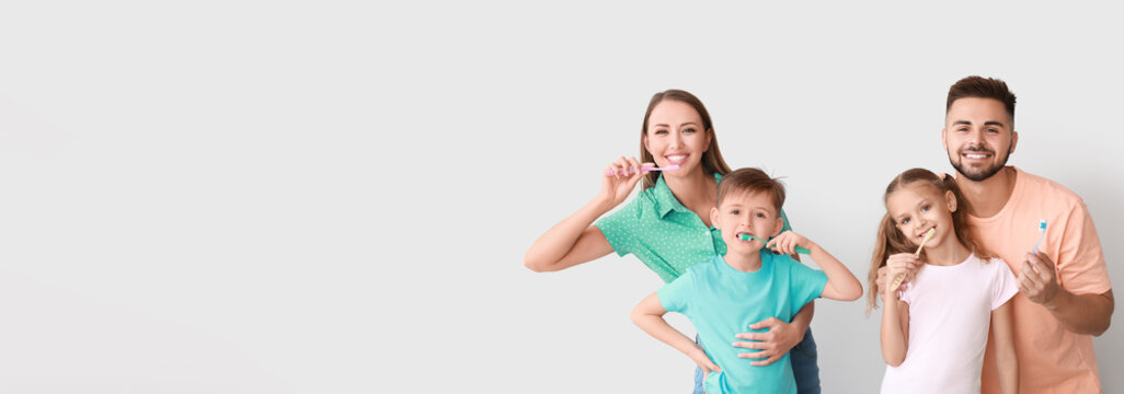 Portrait of happy family brushing teeth on light background with space for text