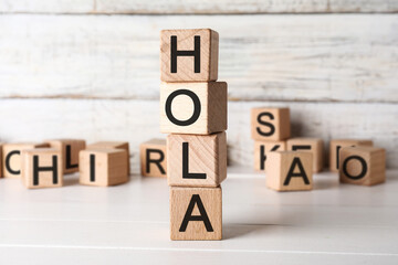 Word HOLA (HELLO) made of wooden cubes on light table