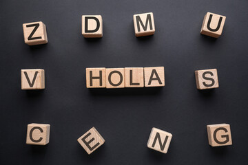 Word HOLA (HELLO) made of wooden cubes on dark background, top view © Pixel-Shot