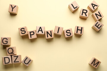 Word SPANISH made of wooden cubes on light color background, top view