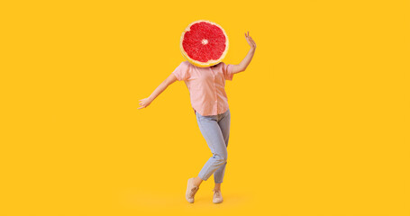 Dancing woman with ripe grapefruit instead of her head on yellow background